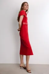 Vestido midi de color rojo, con cuello solapa, manga corta y cierre frontal de botones metálicos. Presenta bolsillos decorativos en el pecho y un cinturón a tono en la cintura.