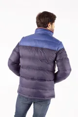 Campera puffer de diseño color block, con parte superior en azul vibrante y parte inferior en azul oscuro. Presenta cuello elevado, cierre frontal completo con cremallera, bolsillos laterales con cierre y logo de la marca estampado en el pecho.