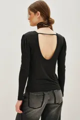 Remera de viscosa en color beige, de manga larga con detalle de frunces en los hombros y un pronunciado escote en la espalda con tira horizontal.