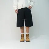 Bermuda baggy de denim negro, de corte ancho y largo por debajo de las rodillas, con diseño de tiro medio y bolsillos clásicos.