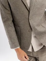 Saco de paño gris con solapa clásica, cierre frontal de botones y bolsillos laterales. Presenta un corte regular fit.