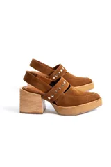 Zapatos tipo zueco de gamuza negra con punta fina y tira sobre el empeine decorada con tachas metálicas plateadas. Posee taco cuadrado de madera y suela con plataforma.
