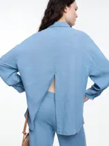 Camisa color coral de calce relajado con abertura en la espalda y mangas largas. Confeccionada en tejido liviano de lino y viscosa. Incluye tres pins decorativos.