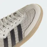 Championes Adidas Samba OG con diseño de malla transpirable y detalles en cuero. Presenta las icónicas tres bandas laterales en negro, puntera reforzada y suela de goma color caramelo.
