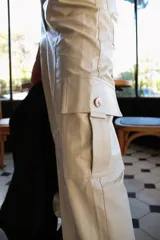 Pantalón cargo de cuerina color beige, tiro alto, corte holgado y bolsillos laterales.
