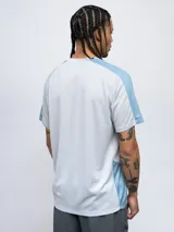 Remera deportiva Umbro de manga corta, color azul marino con detalles en azul claro en los hombros y laterales. Presenta cuello redondo y logo de la marca estampado en el pecho.