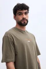 Remera oversize verde militar, confeccionada en 100% algodón, con cuello redondo y diseño relajado. Presenta un pequeño bordado frontal en tono naranja.