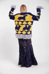 Sweater de lana merino tejido a mano con diseño geométrico y figuras de llamas, corte holgado con cuello redondo y flecos decorativos en el ruedo.