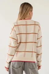 Sweater de punto con diseño de cuadros en tonos beige y marrón, cuello redondo y detalles de borde en color rojo en el cuello y el ruedo.