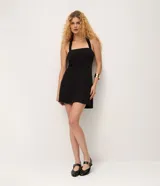 Vestido corto sin mangas en crepé color negro, con escote halter y pollera levemente evasé.