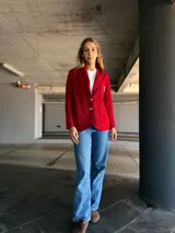 Blazer rojo con solapas, cierre con un botón dorado y escudo bordado en el bolsillo.