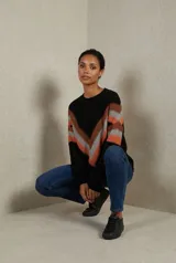 Sweater de tejido tricot con diseño chevron en forma de V en el frente, combinando colores negro, naranja y gris. Presenta cuello redondo, mangas largas y terminaciones en rib.