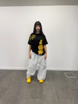 Remera negra de corte regular con estampado gráfico en color amarillo. Presenta inscripciones con estética oriental en la parte superior izquierda y en el lateral derecho. Confeccionada en algodón de alto gramaje con cuello reforzado y grifa de la marca en la manga.