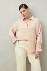 Camisa negra de manga larga con cuello clásico y botones frontales. El tejido presenta una textura arrugada o plisada, y los puños tienen un frunce elástico.