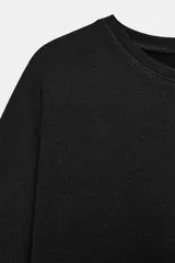 Remera oversize gris melange de tejido fluido, con cuello redondo y mangas cortas amplias.