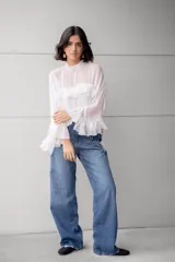 Blusa blanca de gasa con volados en el frente y mangas acampanadas.