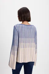 Sweater de punto con diseño de rayas verticales en dos colores, azul y crudo. Presenta cuello bote, mangas largas con terminación acampanada y un aplique decorativo en el pecho.