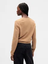 Saco de punto fino color marfil, con cuello redondo, cierre frontal con botones y mangas largas.