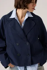 Campera tipo trench corta de corte amplio, color azul marino, con diseño de doble botonadura y cuello con solapas.