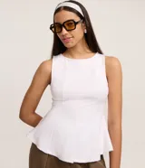 Blusa sin mangas de color blanco confeccionada en tejido punto roma. Presenta un diseño peplum alargado con breteles anchos y volados en el ruedo. Marca Blue Steel.