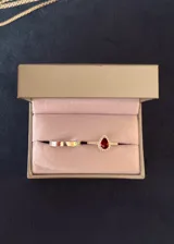 Set de dos anillos de plata 925, compuesto por una alianza de cinta lisa y un anillo con piedra central roja en forma de gota rodeada de zirconias cúbicas.