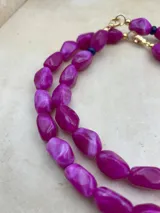 Collar corto de cuentas de piedra fucsia con cierre de gancho dorado y detalles de cuentas azules.