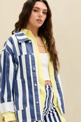 Campera de denim con diseño de rayas verticales en azul y blanco, de corte oversize, con cuello clásico, cierre frontal con botones metálicos y bolsillos appliqués en el frente.