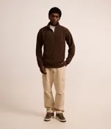 Saco deportivo negro de manga larga, confeccionado en tejido fleece, con cuello alto y cierre frontal parcial de cremallera. Presenta un corte recto y costuras horizontales a la altura del pecho.