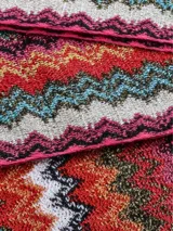 Bufanda tipo chalina de tejido de punto multicolor con diseño en zigzag característico de la marca Missoni y flecos en los extremos.