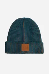 Gorro tejido de punto acanalado en color azul petróleo con detalles en tono tostado. Presenta un diseño con vuelta en el borde y un parche cuadrado de cuero sintético en el frente con logo grabado.