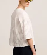 Remera boxy de mangas cortas amplias, color blanco, confeccionada en algodón, con cuello redondo y rayas verticales en las mangas y en la espalda.