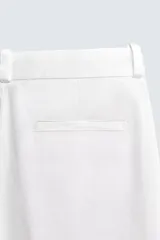 Pantalón chino de corte oversized confeccionado en tejido de algodón con estructura twill. Presenta bolsillos frontales, bolsillos traseros de vivo y cierre frontal con cremallera y gancho metálico oculto.