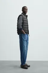 Chaleco acolchado verde oscuro, con cuello alto, cierre frontal con cremallera y bolsillos laterales. Confeccionado en tejido técnico repelente al agua.