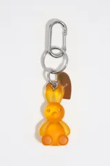 Llavero con dije de conejo de resina color naranja, argolla metálica y mosquetón plateado, acompañado de una placa metálica en forma de corazón.