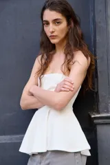 Top strapless de punto con escote recto y detalle de peplum acampanado en la cintura. Cuenta con reborde interno de silicona para mayor sujeción.