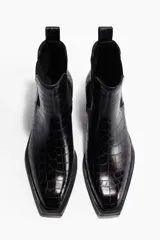 Botas Chelsea de caña media con acabado efecto piel de cocodrilo. Presentan elásticos laterales, punta cuadrada y trabilla trasera para facilitar el calce, con un taco bajo y bloque.