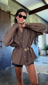 Cinturón de cuero negro con hebilla metálica dorada en forma de sol con rayos.