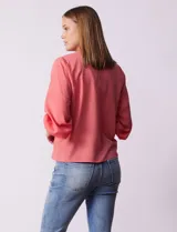 Blusa de gasa con estampado geométrico en tonos negro, gris y celeste. Tiene cuello redondo y mangas 3/4 amplias con abertura y botón.