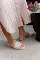 Sandalias planas de diseño minimalista, confeccionadas en una combinación de cuero liso y gamuza en tonos neutros, con detalle de textura tipo reptil en la parte frontal.