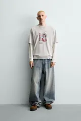 Camiseta relaxed fit color beige con cuello redondo y manga corta. Presenta un estampado frontal de un cartón de leche de fresa con una pajita, texto en japonés y la frase "SWEET MOMENTS".