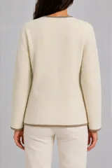 Saco de punto color off-white con bordes en contraste color tostado, diseño de cuello en V, cierre frontal cruzado con botones y dos bolsillos frontales aplicados.