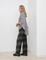 Poncho tejido color crema, con cuello polera y diseño trenzado diagonal en el frente. Presenta un corte asimétrico en el ruedo.