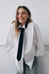 Camisa oversize de algodón con cuello redondo y solapa, manga larga con puño con vuelta y hombro caído. Presenta detalle de tablas en el delantero, cierre frontal con botones ocultos y corbata a contraste incluida.