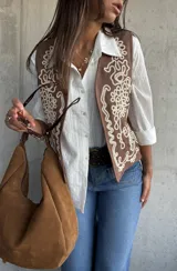 Chaleco de color beige con bordados decorativos en color crema en los paneles frontales. Presenta un diseño sin mangas con corte recto y terminaciones limpias.
