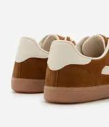 Championes de estilo chuteira, color marrón con recortes y detalles en color crema. Presentan cordones blancos y suela baja de goma color caramelo.