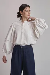 Camisa blanca de mangas largas abullonadas con detalles de calado en los puños y cuello mao.