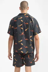 Short de baño negro con estampado de sirenas color naranja y amarillo. Tiene cintura elástica con cordón ajustable y bolsillos laterales.