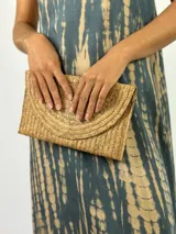 Clutch tipo sobre color beige, confeccionado en fibras naturales trenzadas.