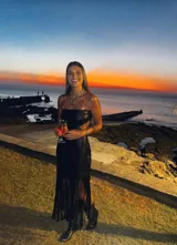 Vestido midi negro de cuero sintético, con escote recto, corte a la cintura y falda recta con flecos.