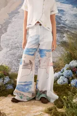 Pantalon largo de corte amplio y fluido, con estampado artístico que simula un paisaje marino en tonos celestes, azules y arena.
